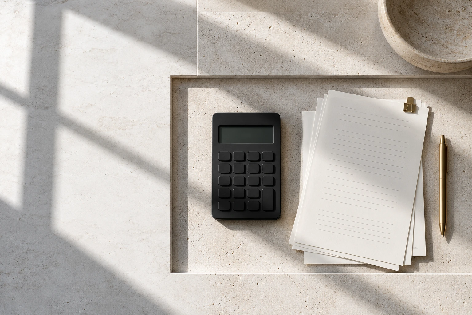 Illustrative finance workbench with organized reconciliation papers, a calculator and a restrained brass pen